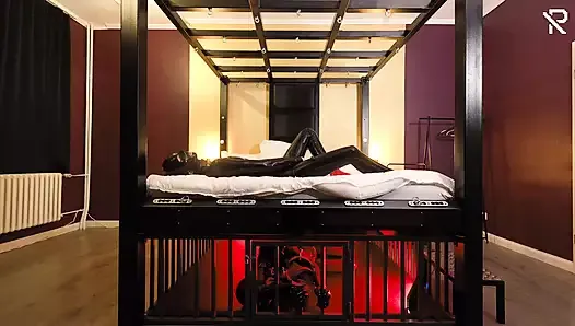 Rubber Nights : l’esclave en caoutchouc se repose fort dans une cage sous le lit