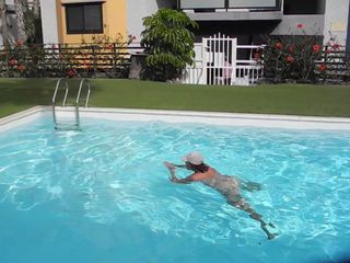 Взрослая женщина купается в бассейне обнаженной