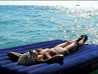 Ich sah am Strand zu, wie ein nacktes Mädchen mit dicken titten sich auf einer Matratze sonnenbadete.