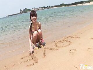 La ragazza giapponese magra si diverte a fare un servizio fotografico su una spiaggia