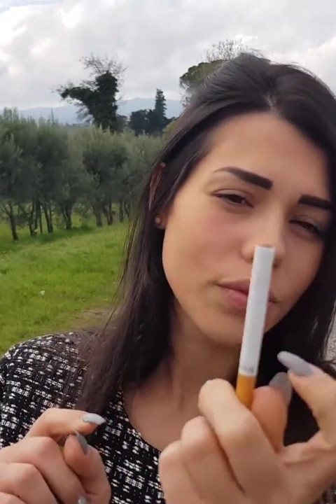 Outdoors smoking cigar from sexy brunette