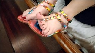 Seksowne czerwone paznokcie i wielokolorowe sandały z stringami