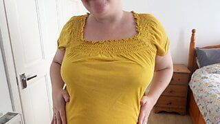 害羞的继母穿着紧身短裤和紧身黄色衬衫摆姿势脱衣服