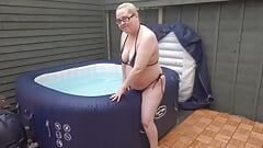 Une femme à forte poitrine en bikini dans le bain à remous