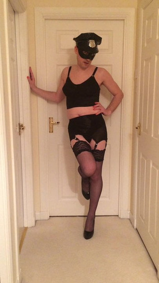 Crossdressing posing in gay cop lingerie stockings and heels