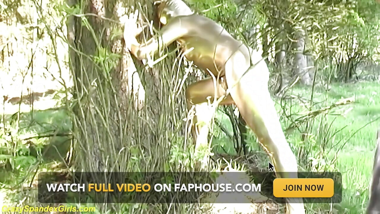 ぴったりとしたゴールデンのスパンデックスキャットスーツを着たセクシーな黒檀の美女が屋外でポーズをとる