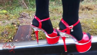 Lady L, прохаживающаяся по металлической дороге с сексуальными красными высокими каблуками!