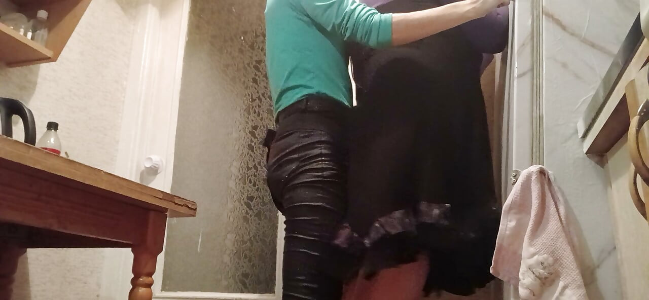 I’m fucking my married neighbor hard with a strap-on in the kitchen while her husband watches TV