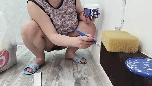 Orta yaşlı seksi kadın külotsuz bir kaloriferi boyar.