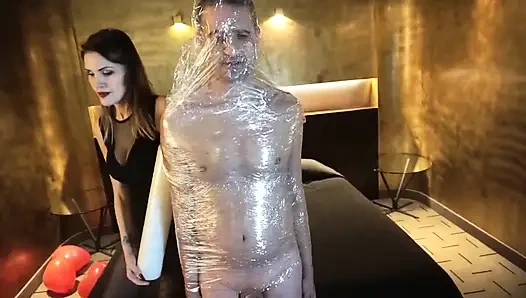 Женское доминирование, девушка засовывает свою рабыню в бондаж с клейкой лентой