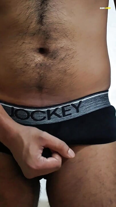Young man wearing black underwear is dancing cock while holding his groin area.