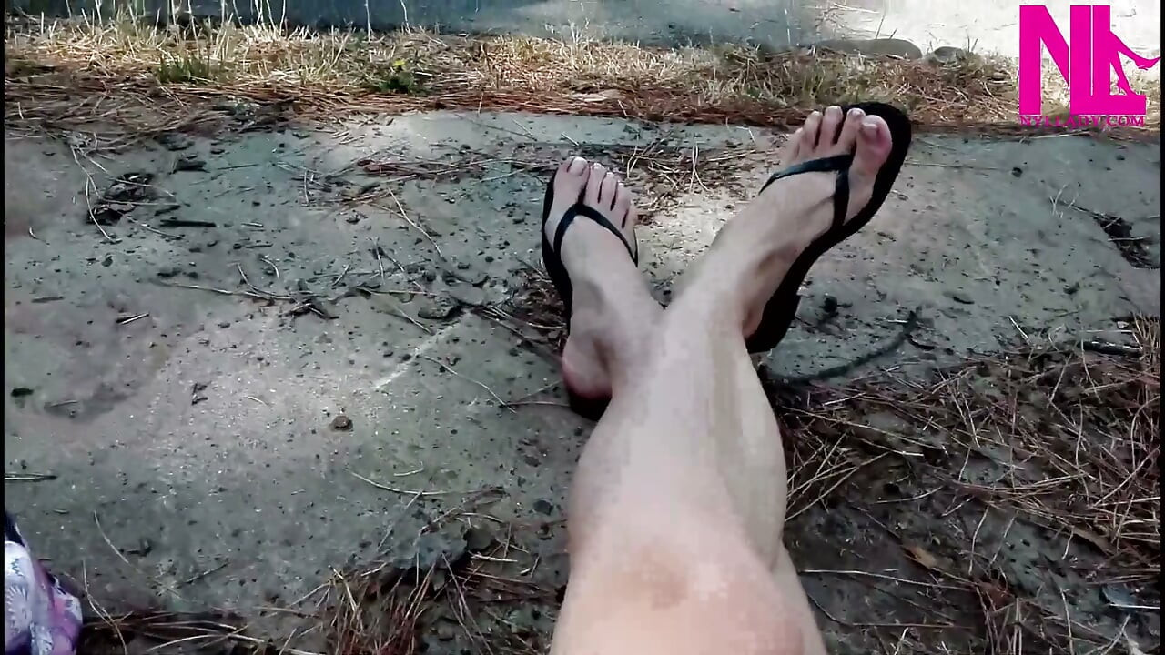 Gal dingling i mine svarte skinnflipflops i en park
