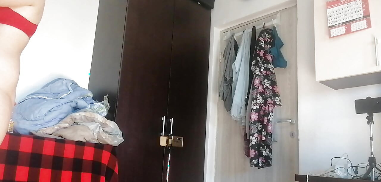 Amaterska žena pleše gola kod kuće. Amaterska žena se zabavlja isprobavajući odjeću i šišajući je.