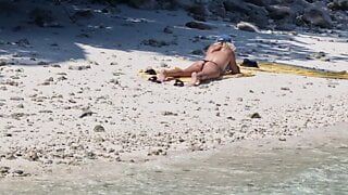 Voyeurs - une fille nue sur la plage touche sa chatte