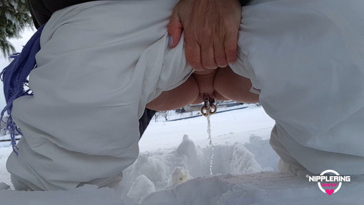 Amante dell'anello del capezzolo che piscia all'aperto nella neve, esibendo enormi capezzoli con piercing e figa con piercing con labbra allungate