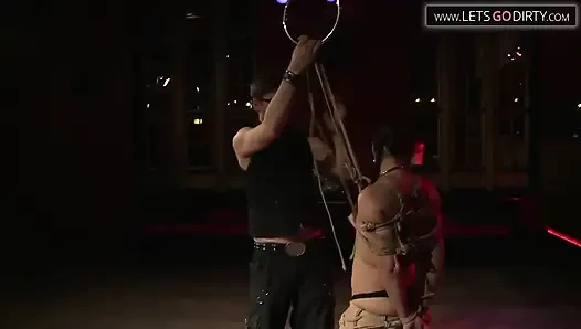 Esmer kadının elleri ve bacakları iplere bağlıyken göğüsleri okşuyor