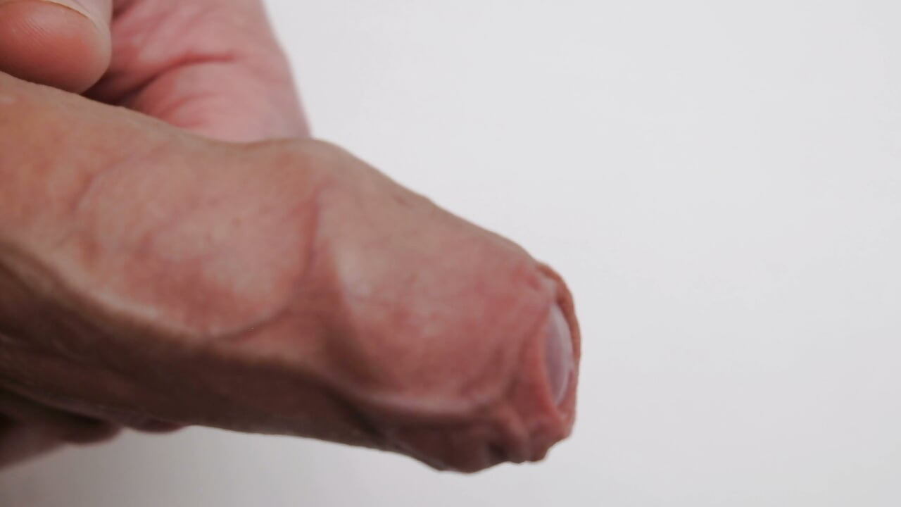 Very Close up foreskin and bell-end a man plays with the gland of his erect uncut cock