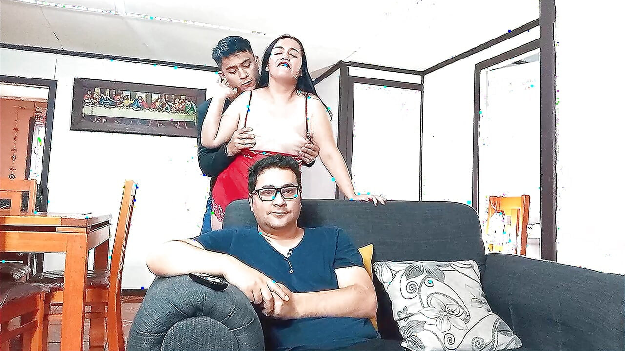 Unfaithful stepmother is fucked by her stepson behind the back of her cuckold husband who watches TV