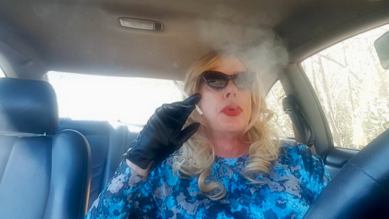 Gilf blondă matură care fumează țigări lungi în timp ce își conduce mașina