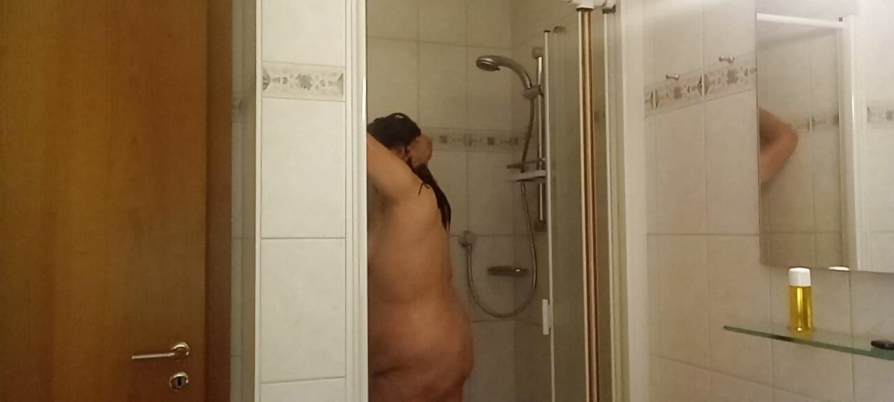 Skutečná žena sprchuje měkké břicho, mokrá kůže