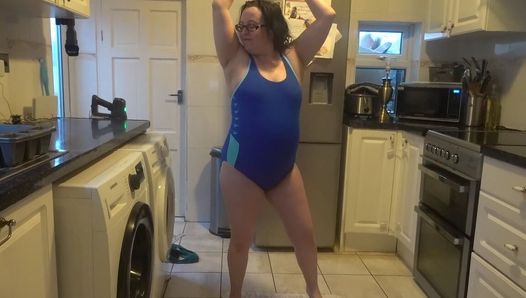 Ehefrau mit großen brüsten tanzt im engen blauen badeanzug