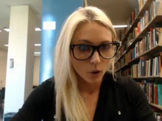 Leuk blond universiteitsmeisje dat in de bibliotheek knippert