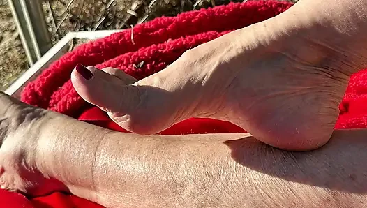 Hayran isteği nine güneşte çıplak kirli sert tabanlarını ve ayak parmaklarını gösteriyor