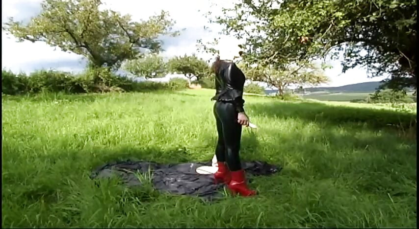 Fetišská otrokyně v latexu chodí a saje robertek na trávě
