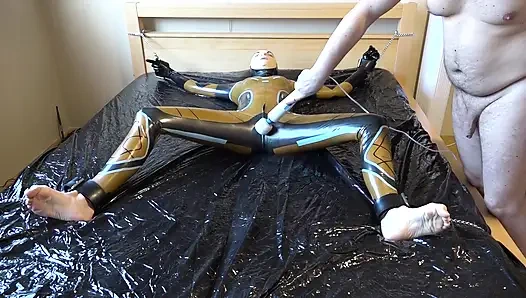 Latex Danielle is attached to the bed and masturbated with the massage vibrator