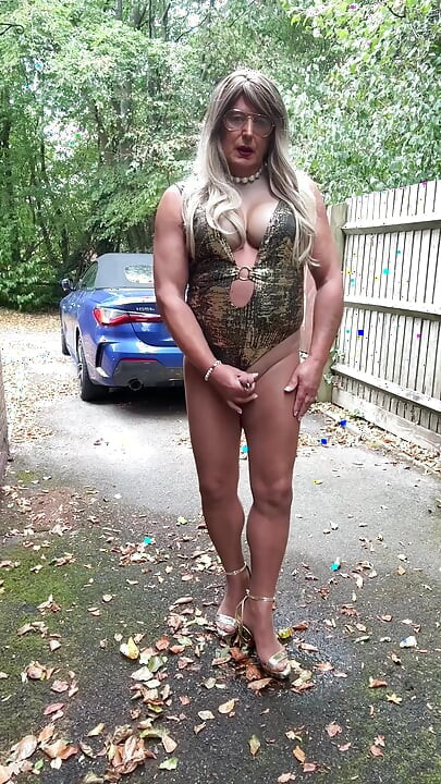 Seksi transvestit kellycd2022 u zlatnom kupaćem kostimu i štiklama čisti lišće