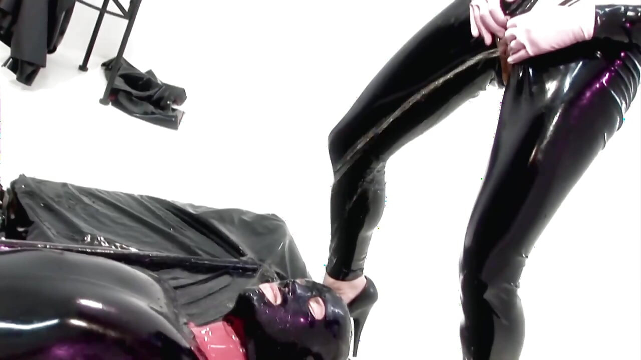 Dominatrix de látex sentada no rosto de um escravo