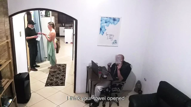 While the husband works, the wife in a towel greets the delivery man.