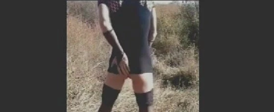 Masturbating in black dress outdoors.