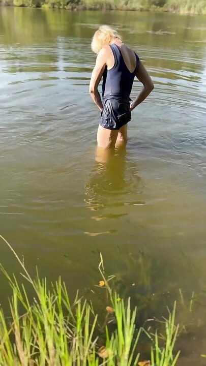 Trans djevojka pliva u jezeru u plavoj sportskoj haljini. Wetllok trans djevojka mokra.