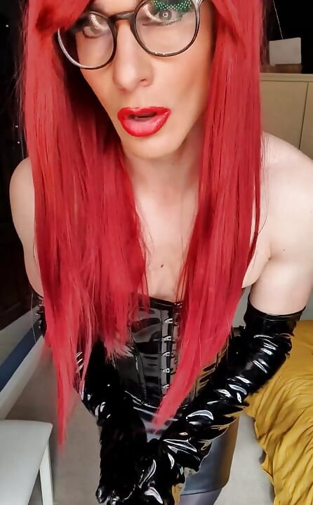 Hou je van roodharige? Verkleed in kinky pvc en zachte glanzende panty trekt meesteres Jessica haar lange pvc-handschoenen aan