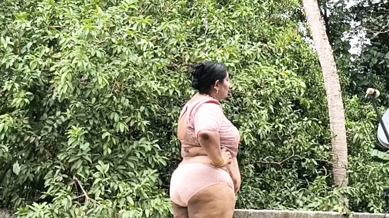 A full-figured woman in a white skirt and pink top strips down and walks nude outside.