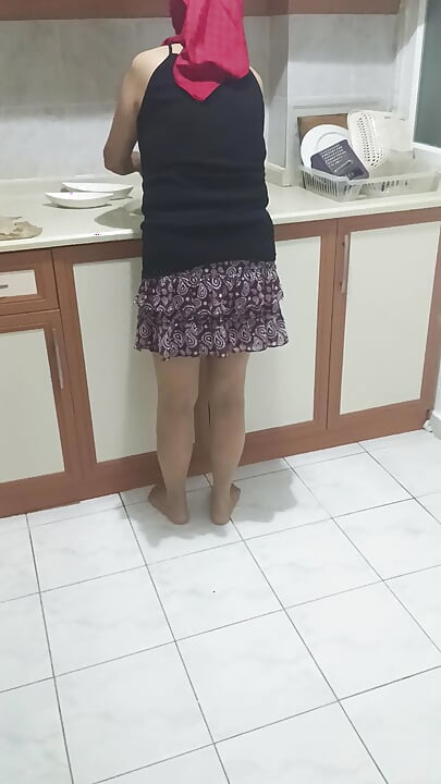 Mature woman in sheer stockings doing housework in the kitchen.