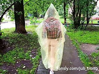 Meisje in een regenjas met tieten en kont op de straten van de stad