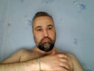 Behaarter Typ mit Bart spielt mit seinen Brustwarzen