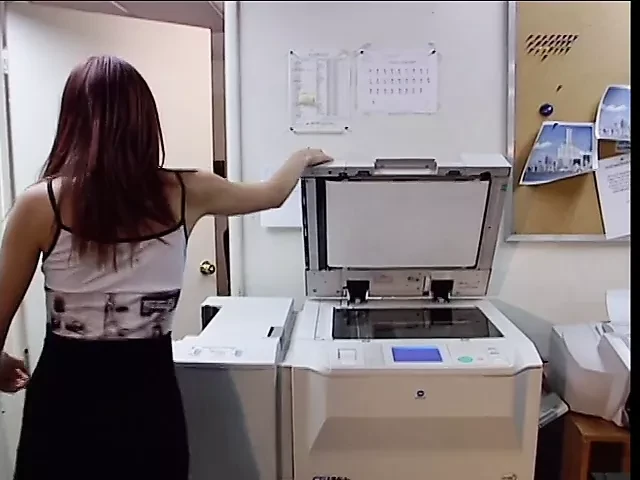 Cute peacheriono with flaming auburn hair  asked her work fellow to explain how to use the new copier