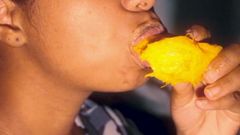 Sexy Ebenholz im Mund spielt mit einer Mango