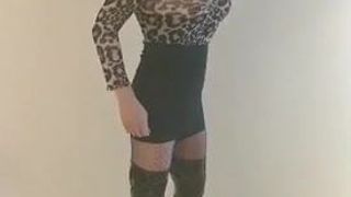 Sexy Transvestit, die ihren Körper mit falschen Titten in ihren hohen Stiefeln zur Schau stellt