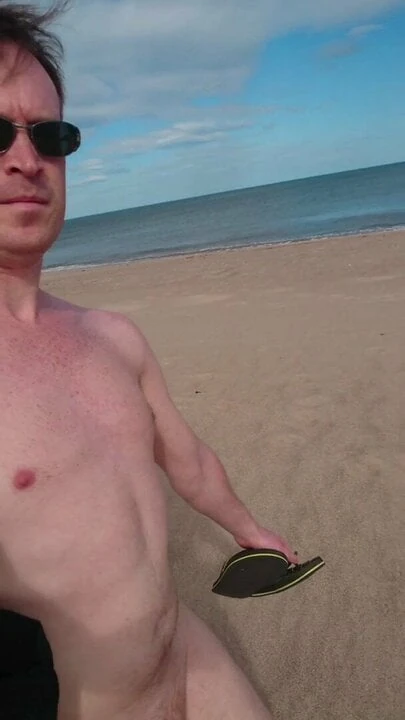 Dad walking alone on beach naked
