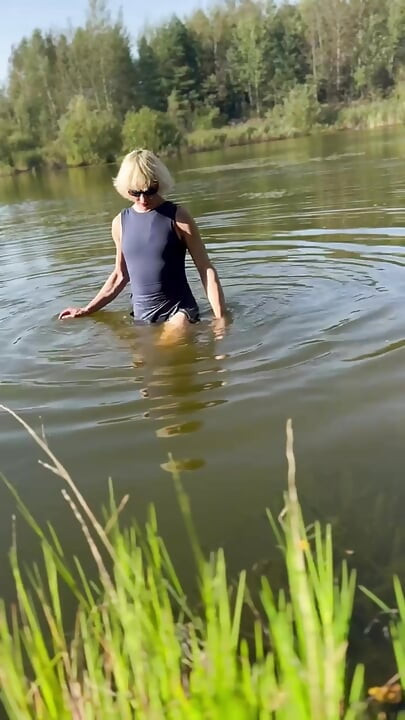 Trans djevojka pliva u jezeru u plavoj sportskoj haljini. Wetllok trans djevojka mokra.