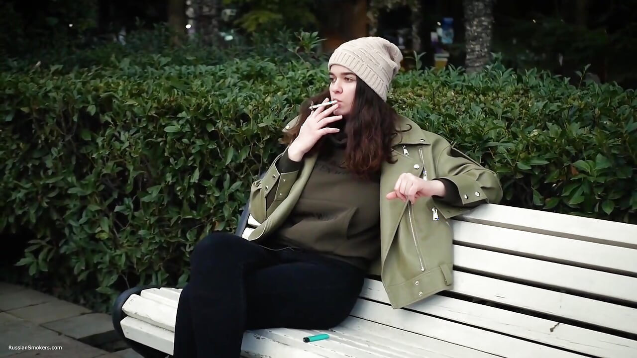 Une jeune brune fait une promenade sans hâte avec une cigarette de 120 mm