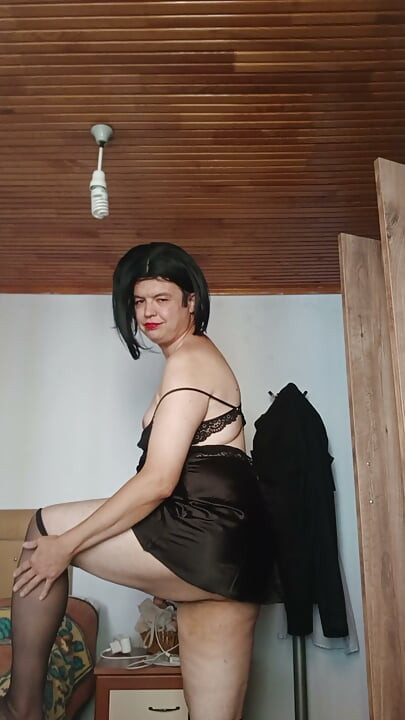 장난스러운 블랙 란제리를 입고 발로 서서 포즈 취하는 섹시한 CD