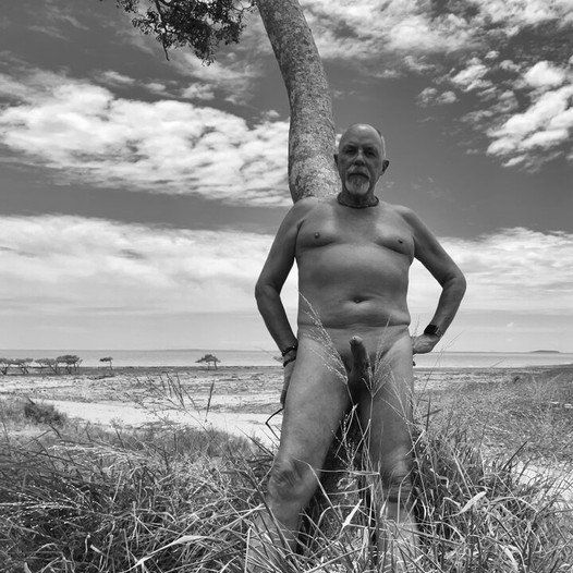 Jugando afuera en la playa desnuda y erecta