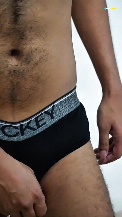 Young man wearing black underwear is dancing cock while holding his groin area.