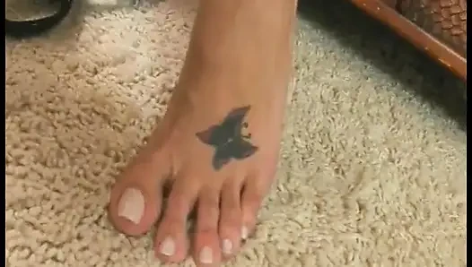 Horny brunette plays with her feet before masturbating with a toy on the sofa