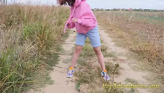 Hipster-mädchen mit einem hoodie pinkelt ihre jeans und pinkelt neben dem autorad